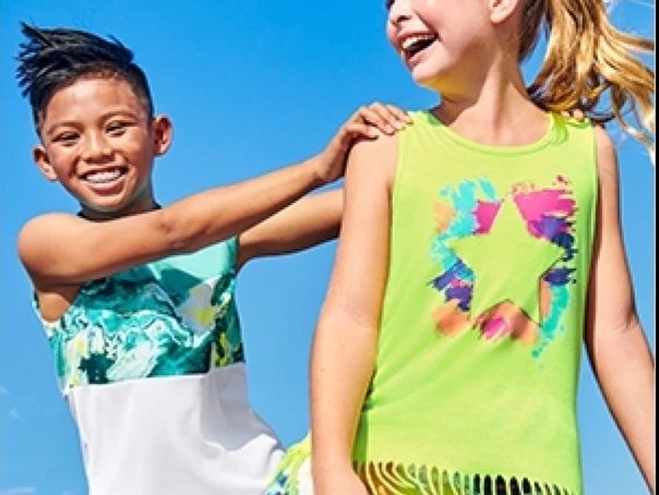 Dos niños con ropa de verano de Pekes sonriendo bajo el cielo